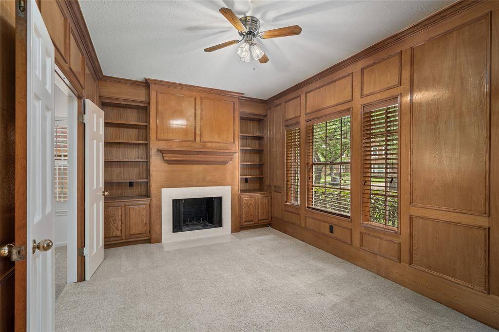 Just off the entry, a distinguished home office awaits—complete with rich wood paneling, a warm fireplace, and classic French doors. This inviting space offers the perfect blend of functionality and sophistication for working or relaxing in style.