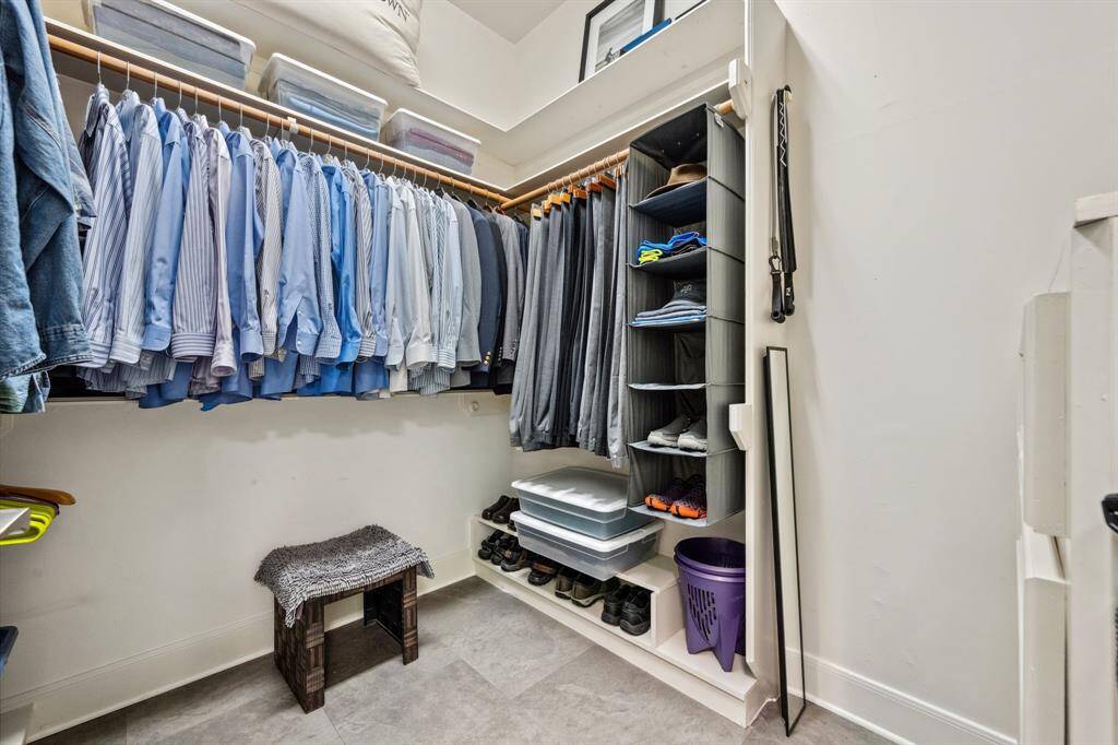 This generously sized primary closet offers plenty of storage space, featuring built-in shelving and racks to keep your wardrobe organized and easily accessible. Perfect for those who appreciate both functionality and style in their storage solutions.