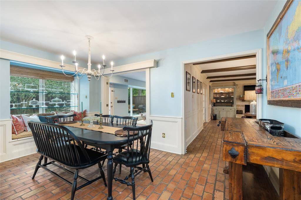 The dining room features rich brick floors and stylish glass shelving, adding a touch of sophistication. Large windows with built-in bench seating frame stunning views of the lush outdoors, making this space perfect for both formal dining and quiet moments of reflection.