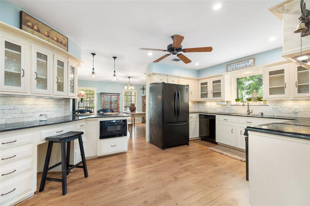 The kitchen is thoughtfully designed with glass-paned cabinet doors, offering easy access to your favorite dishware. Pots and pans drawers add convenience, while under-cabinet lighting creates a warm ambiance. The beautiful stone backsplash ties everything together, making this space as functional as it is stylish.