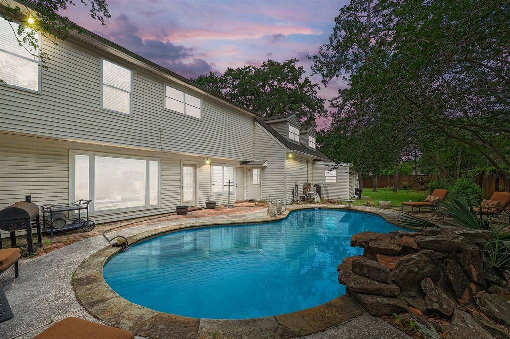 Spacious backyard features a sparkling pool with a tranquil waterfall feature, perfect for relaxing or entertaining. The generous patio surrounding the pool offers plenty of space for outdoor living and dining, all set in a private, serene setting.