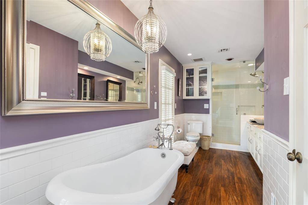 The thoughtfully updated primary bath features a serene garden tub, elegant light fixtures, and a seamless shower for a spa-like experience. Dual sinks provide convenience, making this space both beautiful and functional.