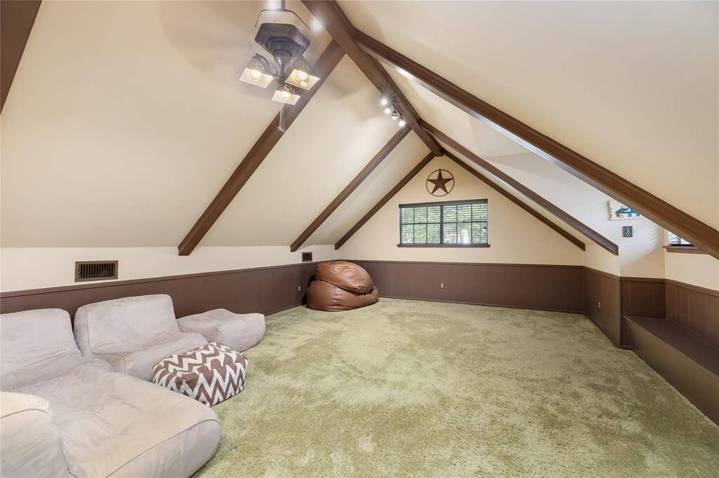 This expansive playroom offers plenty of space to create a dream area for kids or adults alike. A built-in bench adds a charming touch, while exposed beams on the vaulted ceiling create a sense of grandeur. The room’s open layout allows for endless possibilities, from games and creativity to relaxation and gatherings.