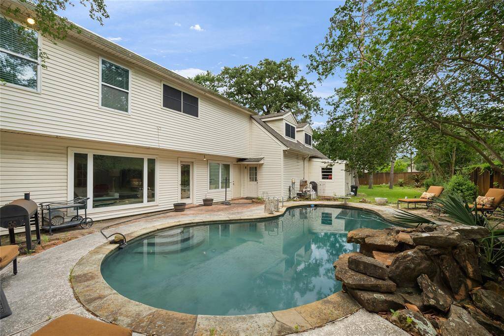 The pool area features elegant steps leading into the refreshing water, complemented by a soothing waterfall feature. With plenty of space to host gatherings or simply relax, this backyard oasis is the perfect spot to cool off and enjoy the outdoors.
