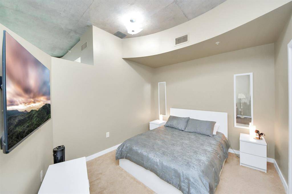 Generously sized bedroom featuring a sleek curved wall that separates the sleeping area from the living space, offering both privacy and an open, airy feel