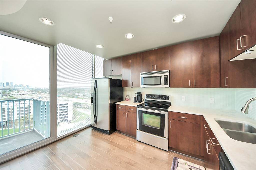 Enjoy cooking with a view! This kitchen is bathed in natural light from large windows, offering a stunning cityscape as your backdrop.