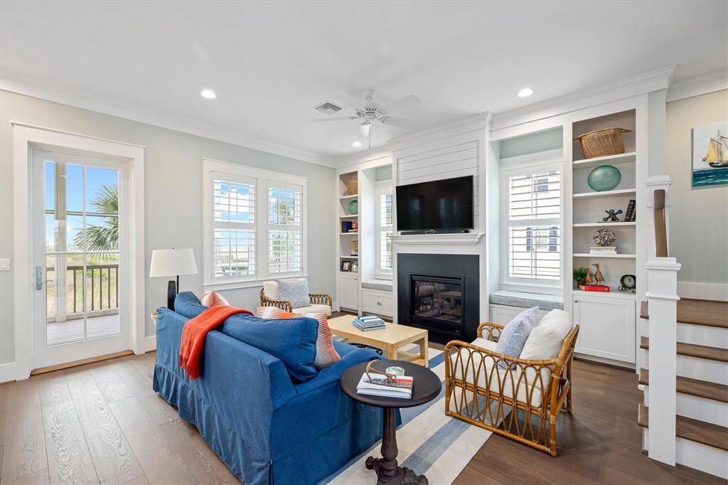 This cozy living room features a bright, airy design with large windows, built-in cabinetry, and a gaslog fireplace.