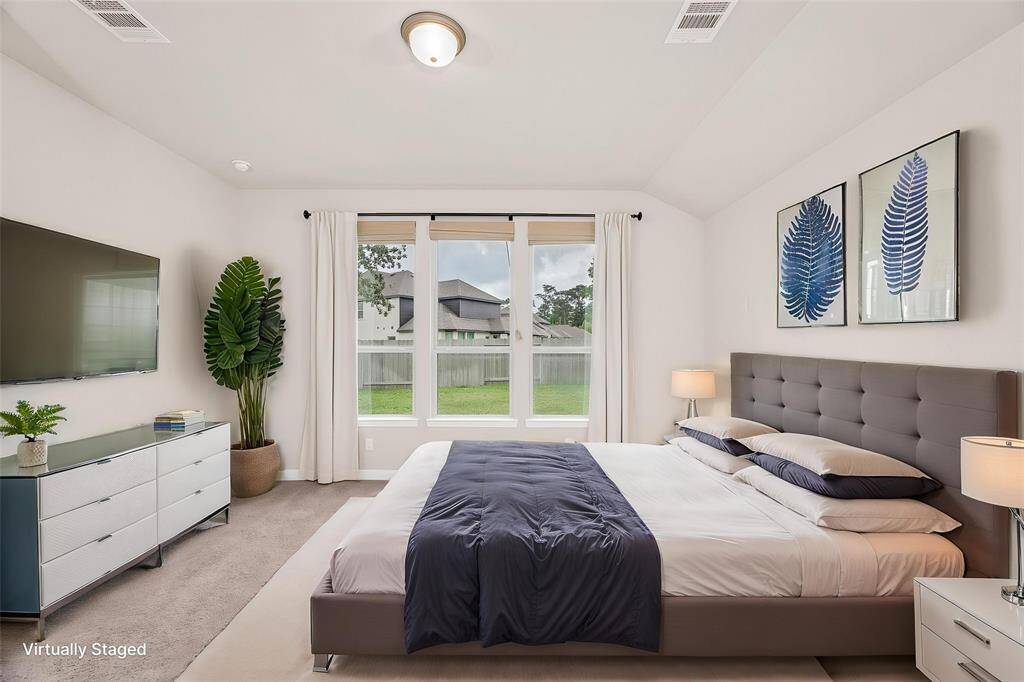 Primary Bedroom with Sloped Ceiling and Large Window. Please Note: TV is Virtually Staged
