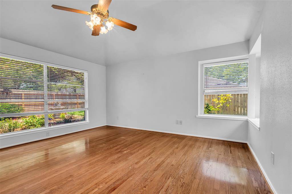 The Primary Bedroom has a raised ceiling, ceiling fan with lighting, large windows for natural light, wood flooring and a walk-in closet (not in photos).