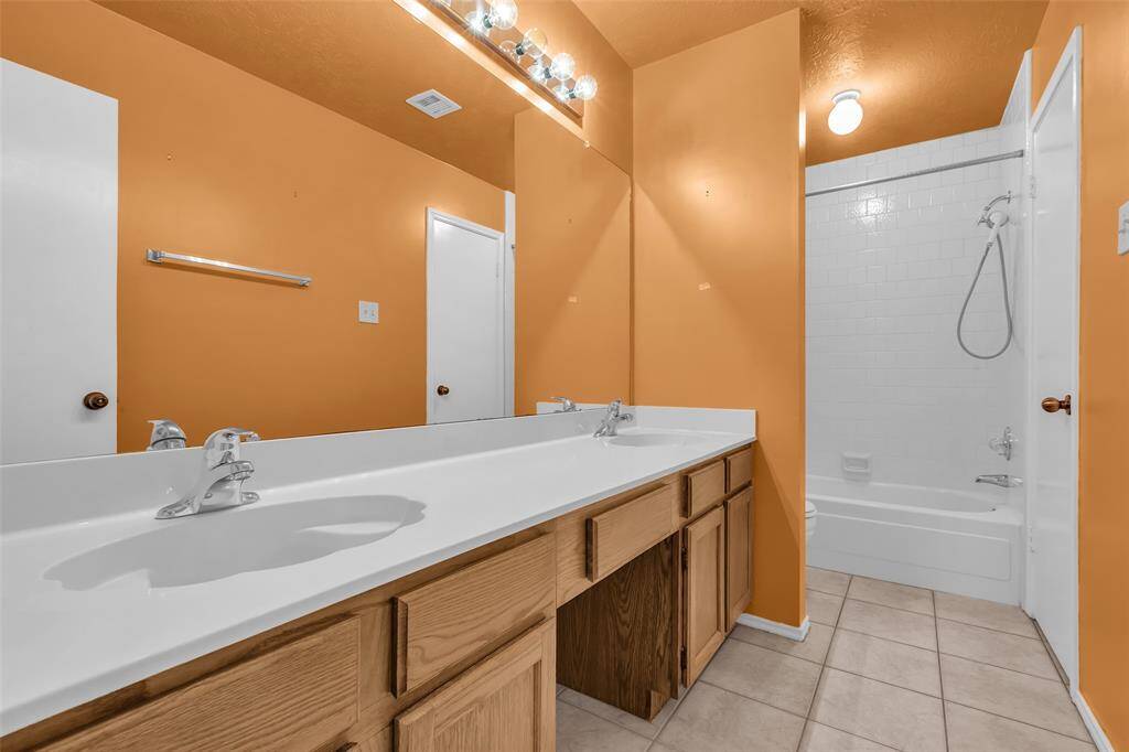 Bath 2 features dressing area with dual sinks, tile flooring and a tub/shower combo with tile walls.