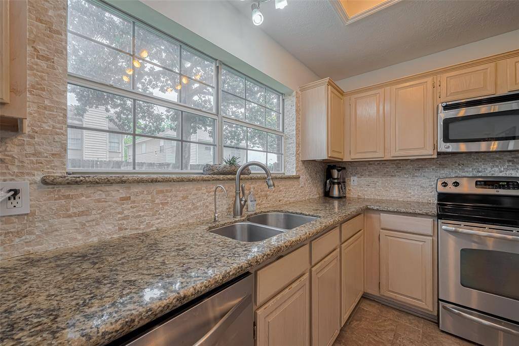 Bright and inviting kitchen featuring large windows, sleek stainless steel appliances, and elegant granite countertops. Perfect for culinary enthusiasts and entertaining guests.