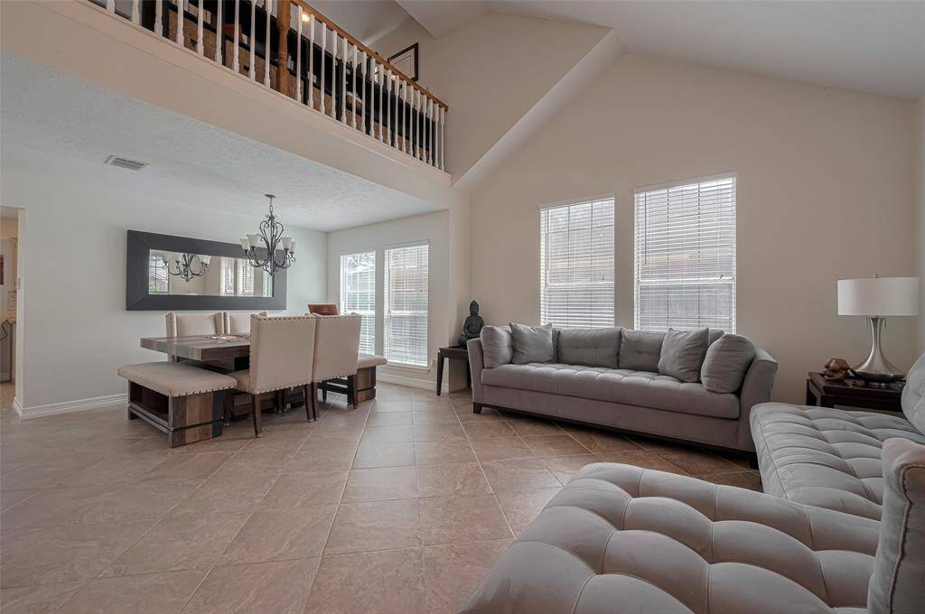 Spacious open-concept living and dining area with soaring vaulted ceilings, abundant natural light, and elegant modern finishes.