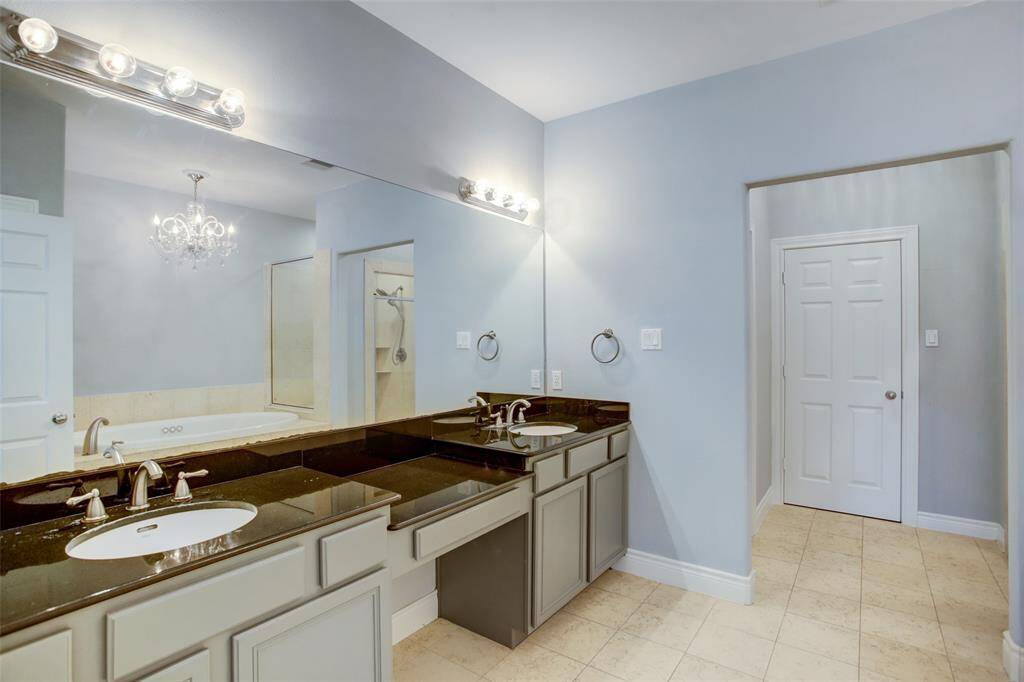Primary bath with a double sink vanity, granite countertops, designer faucets.