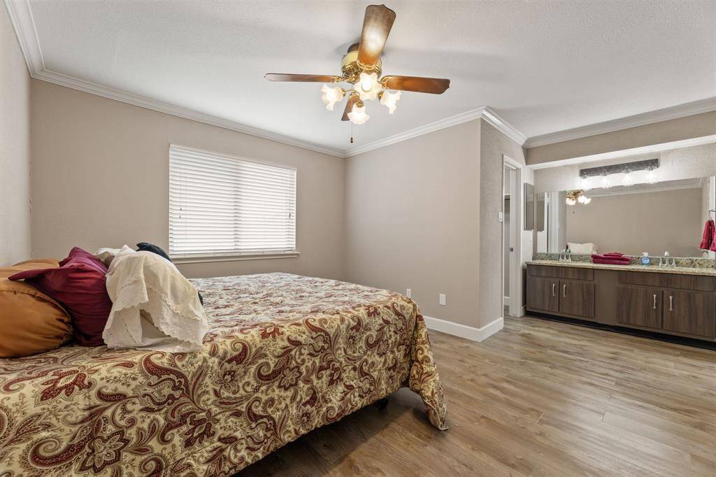 Primary bedroom with a dual sink vanity, ceiling fan