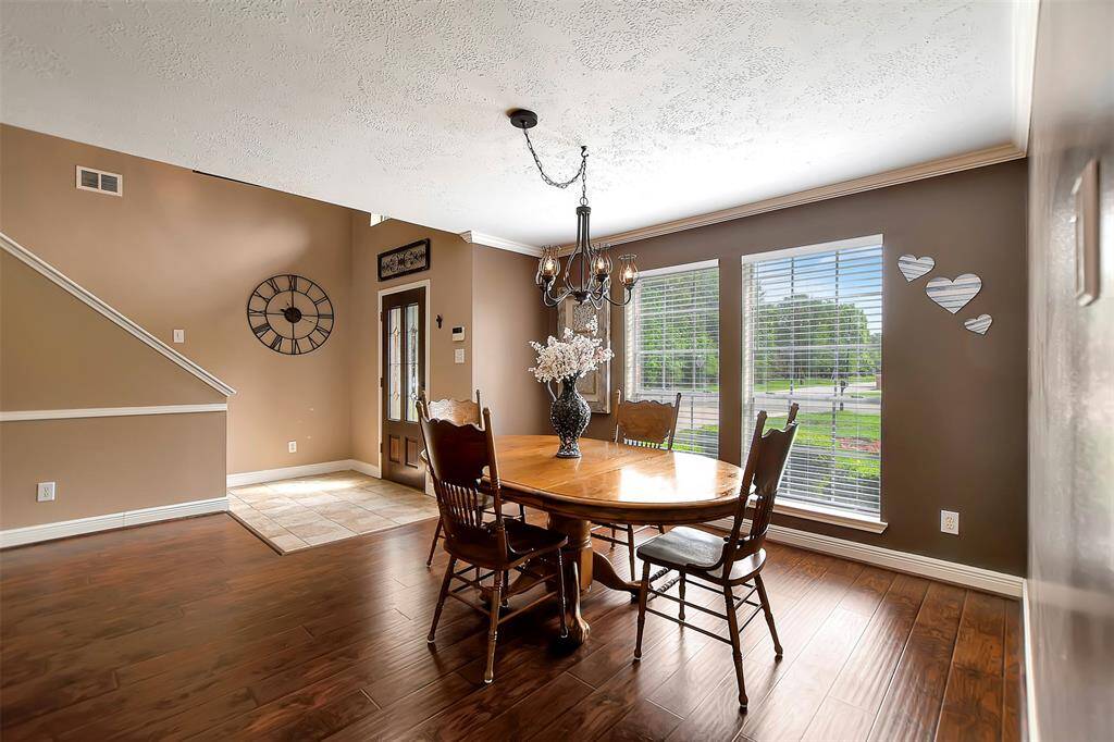 This dining area features warm brown walls and wood flooring. It has large windows for natural light.