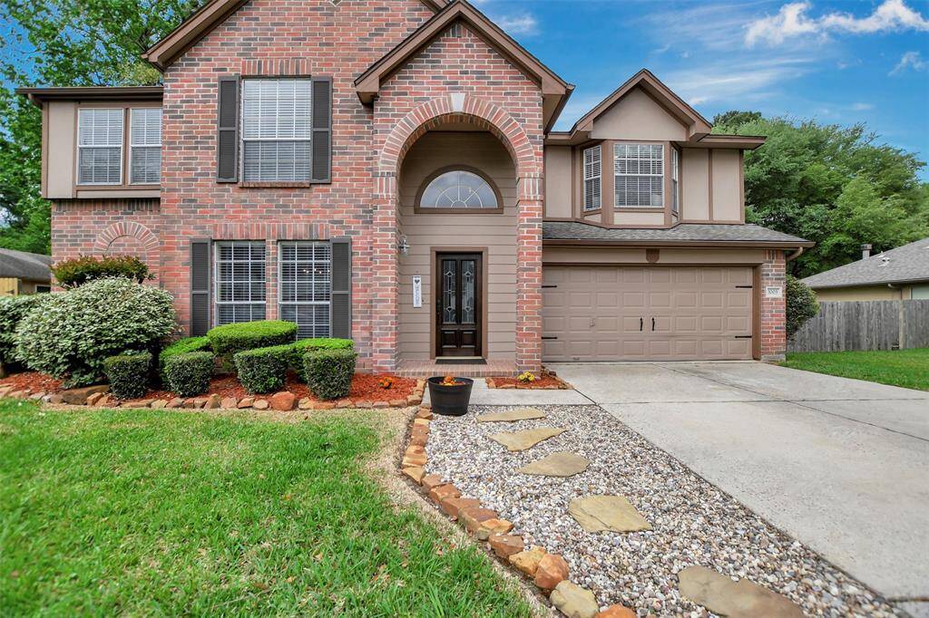 Two-story brick home features a charming arched entryway and stone pathway.