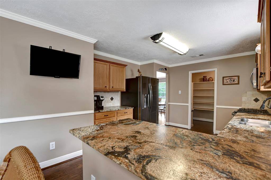 The kitchen includes a pantry, a mounted TV, and offers a view into the dining area.