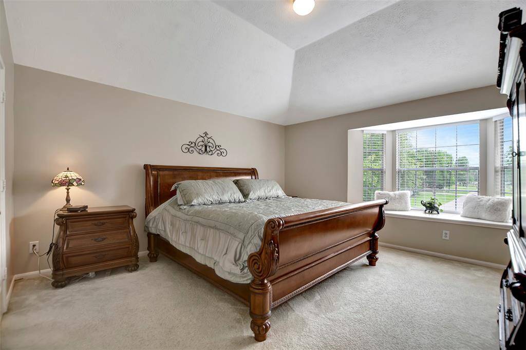The primary bedroom features a vaulted ceiling and a large window with a cozy seating area.