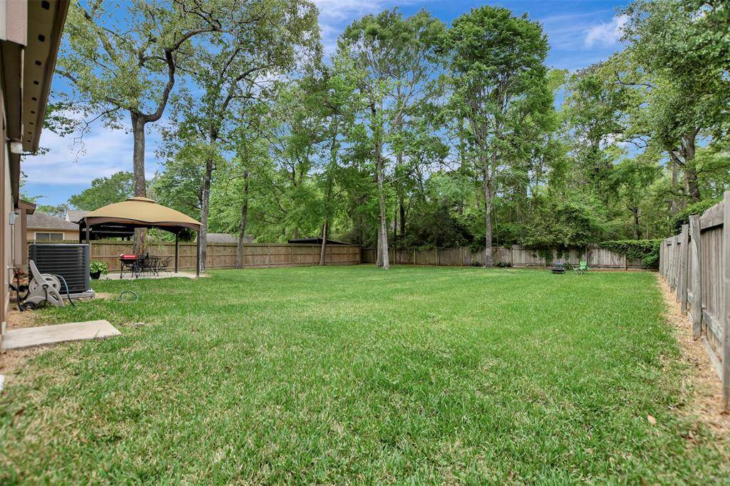 Spacious backyard is ideal for relaxation and entertaining. Tall trees offer shade and a natural backdrop.