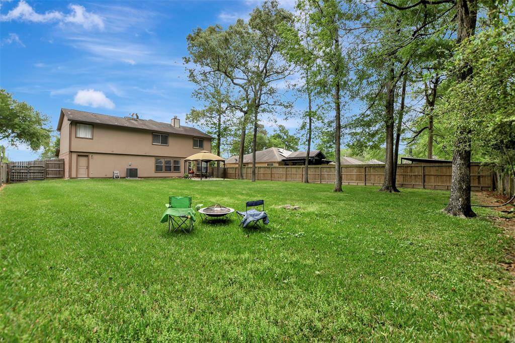 Spacious backyard has mature trees & is perfect for outdoor activities and relaxation, enclosed by a wooden fence for privacy.