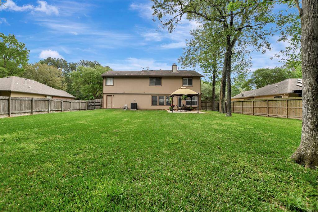 This spacious backyard features a large, well-maintained lawn with mature trees and a cozy patio area, perfect for outdoor relaxation and entertaining. The two-story home offers privacy with a fenced backyard.