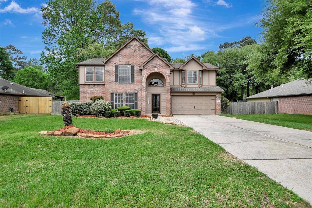This is a two-story brick home with a neatly landscaped front yard and a spacious driveway leading to a 2 car garage.