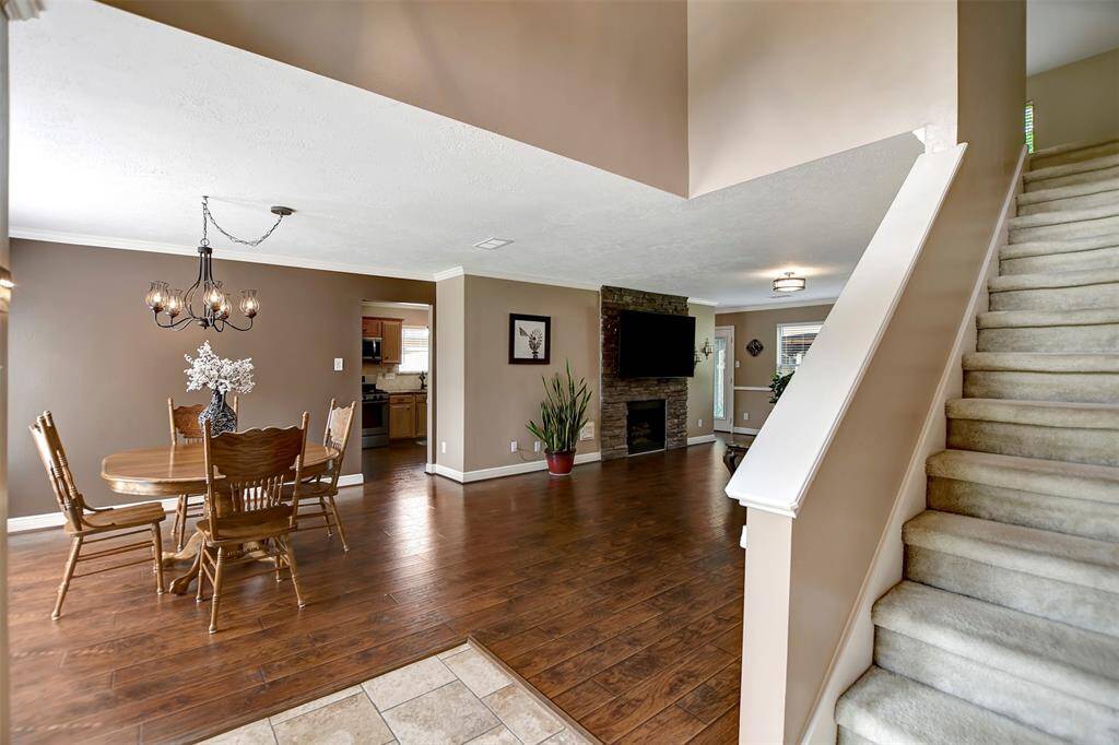 This welcoming home features an open-plan living and dining area with warm wood floors and a cozy fireplace. The dining space is adjacent to the kitchen, and a staircase leads to the second floor.