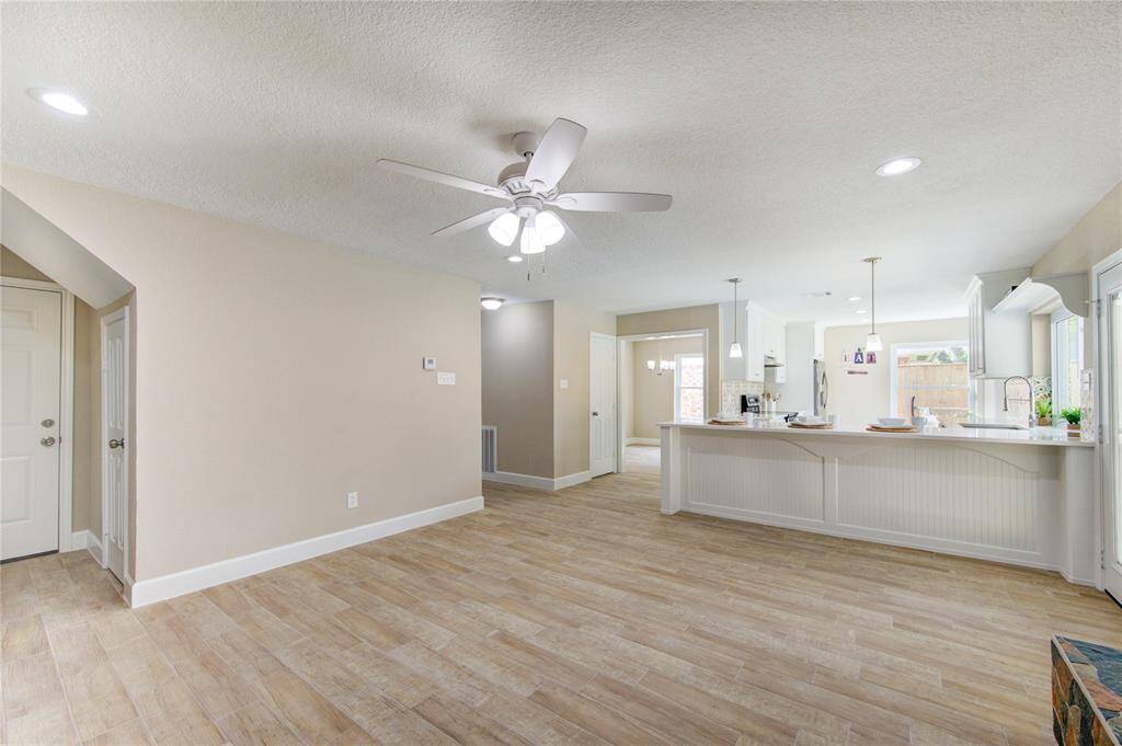 This photo showcases a spacious, open-concept living area. The room seamlessly connects to a bright kitchen with a large island and modern appliances. Natural light floods in through large windows, creating a warm and inviting atmosphere.