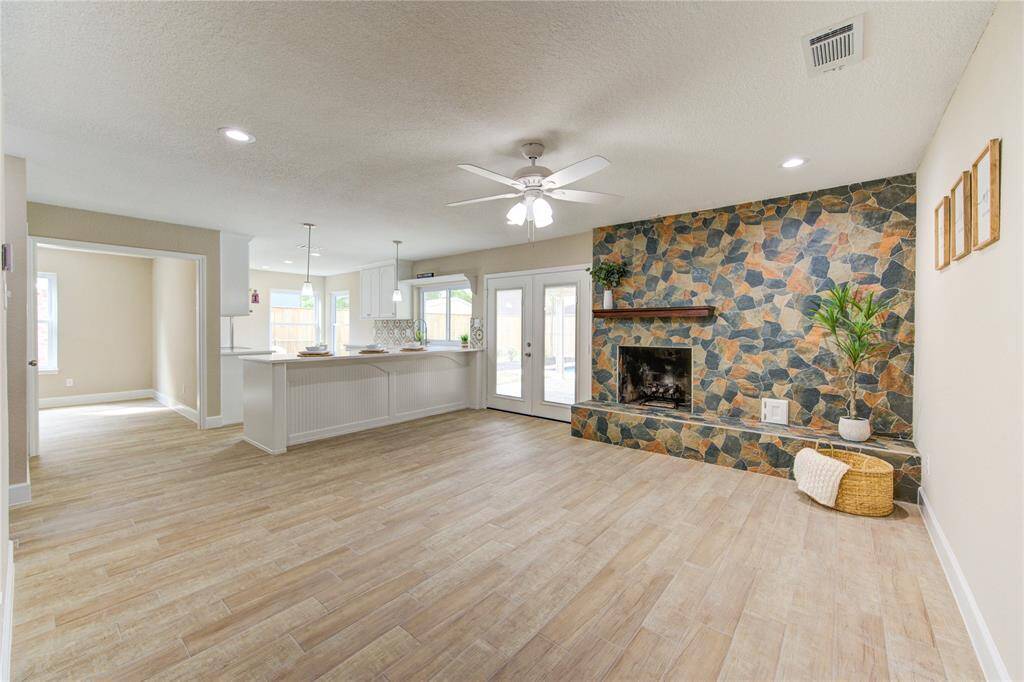 Another view of the spacious open-concept living area. Natural light fills the room through large windows and glass doors.