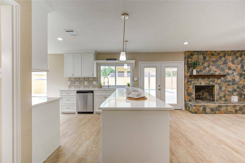 Check out the  bright, open-concept kitchen and living area. The kitchen features a large island, white custom cabinetry, and a stylish tile backsplash.