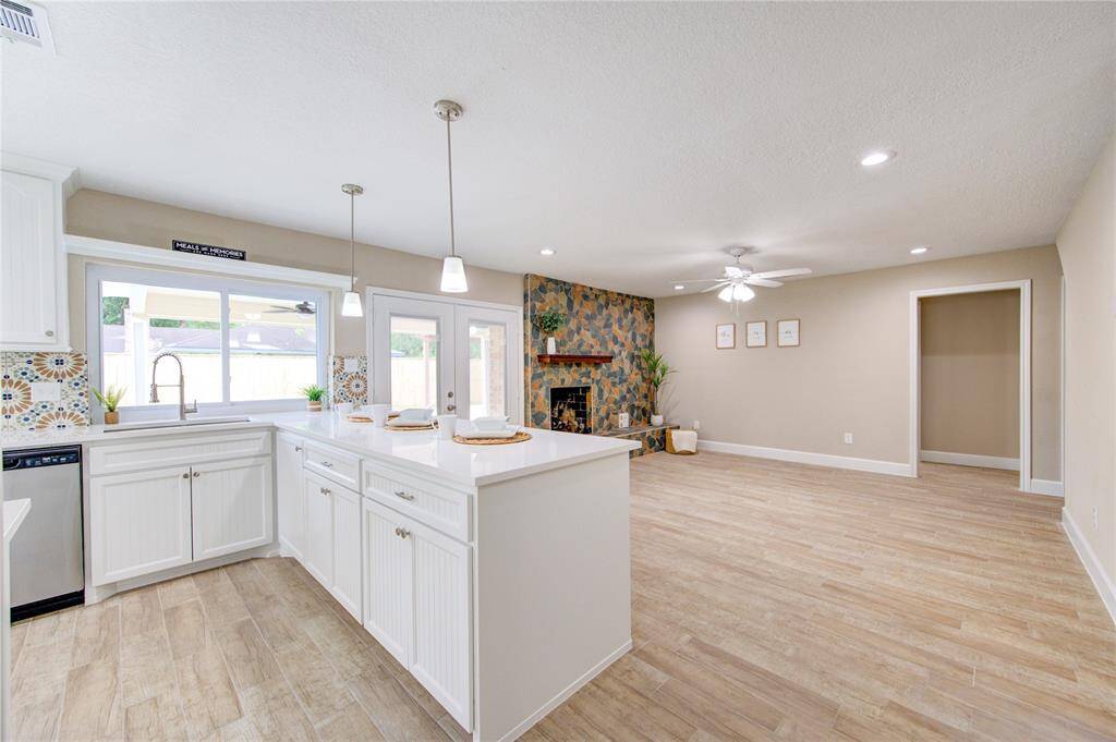 Another view of the bright and open kitchen-living area with ample lighting and idyllic picture windows facing the backyard.