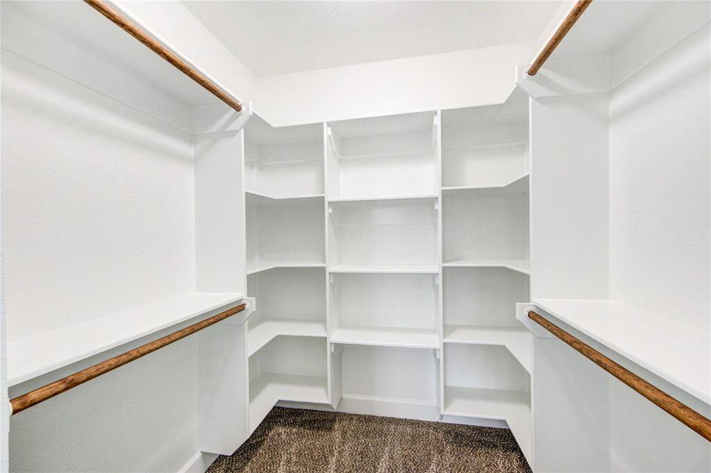 This is the closet for bedroom #3. It showcases a spacious walk-in closet with abundant shelving and hanging space. The clean white finish and ample lighting create a bright, organized environment for storage.