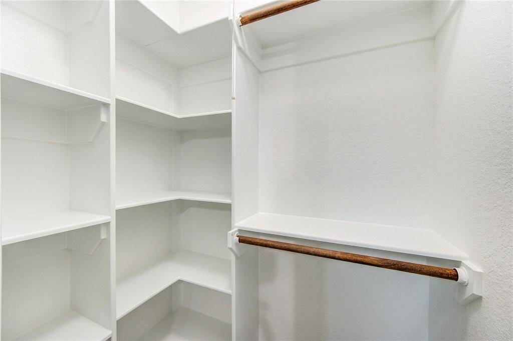 This photo shows the spacious, well-organized walk-in closet in bedroom #4. It features multiple custom built shelves and hanging rods, ideal for maximizing storage and keeping clothing neatly arranged.