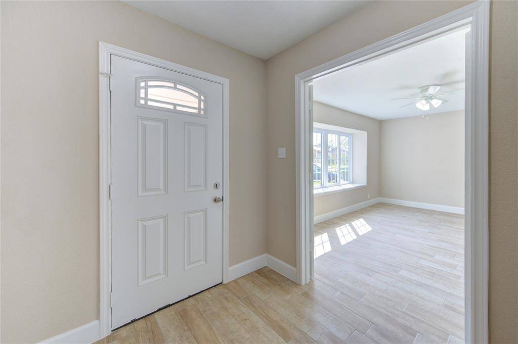 Step inside to a bright, welcoming entryway. Note the gorgeous light wood-like tile flooring that runs continuously throughout most of the home.