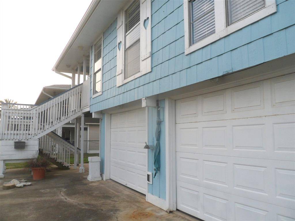Back of the home showing garage doors on canal side and covered deck.