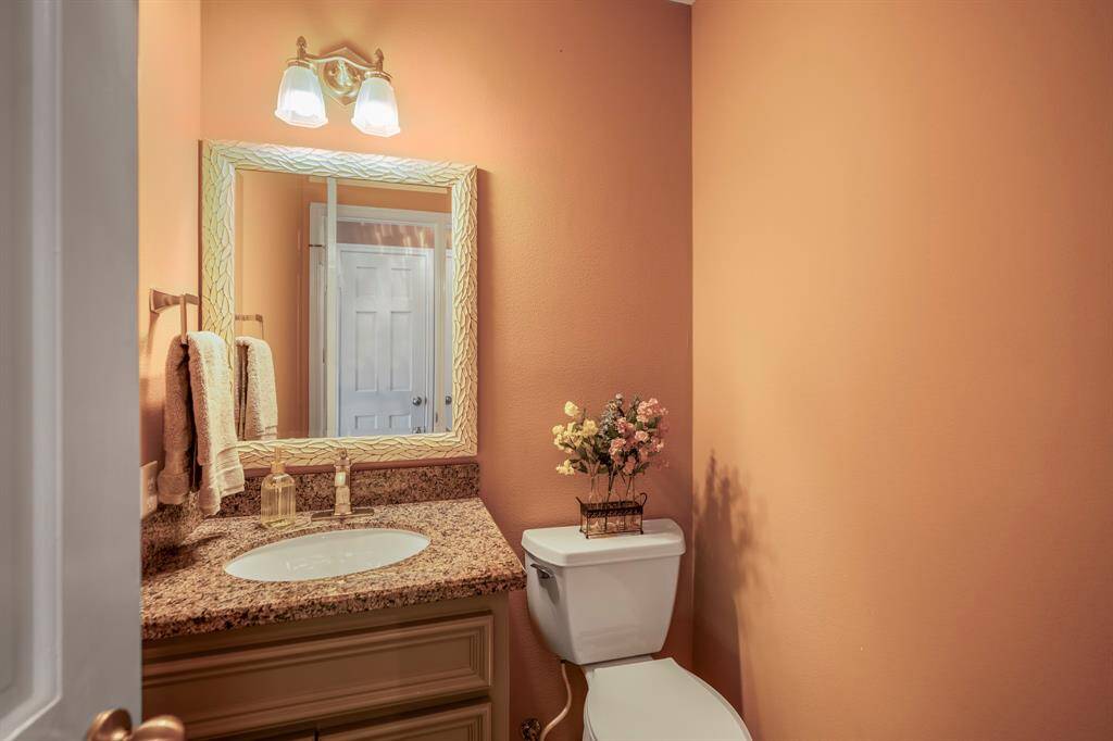 First floor secondary half bathroom features a single vanity with granite countertop