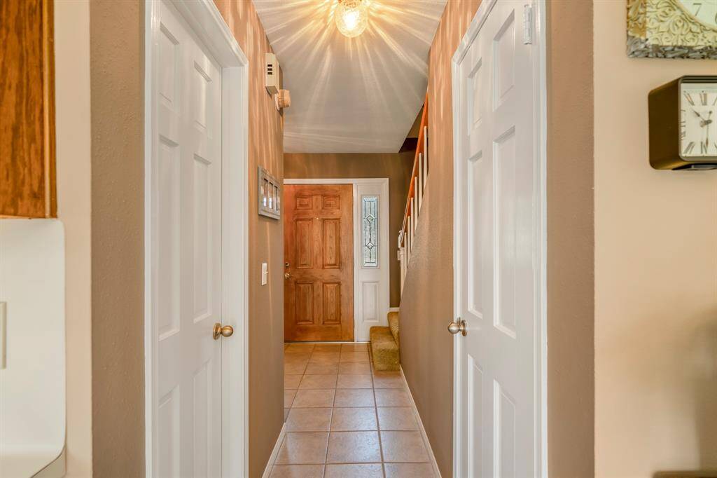 The hallway leads you back to the front door, and features warm neutral tones, and tile flooring.