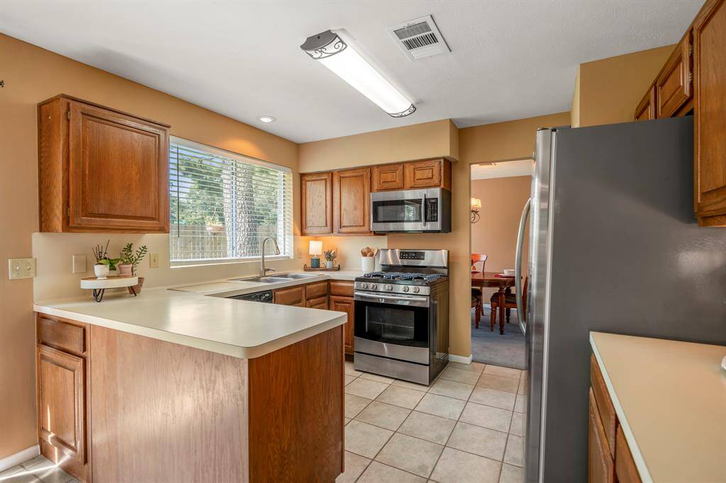 This is a well-lit kitchen with wooden cabinetry, modern appliances, and large window overlooking the backyard.