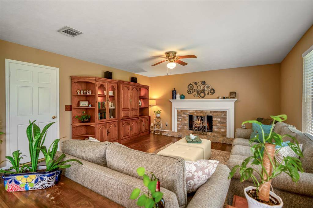 Family room features a warm color palette, laminate wood floors, a classic fireplace, and ample natural light.