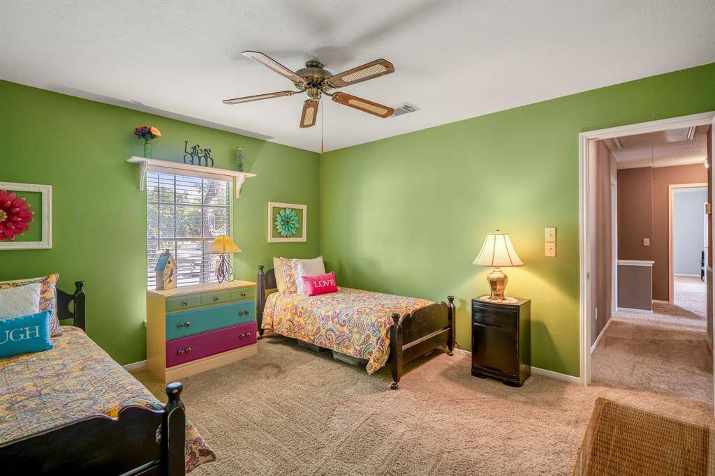 This secondary bedroom features a vibrant paint color, ceiling fan for added comfort and large window for natural lighting