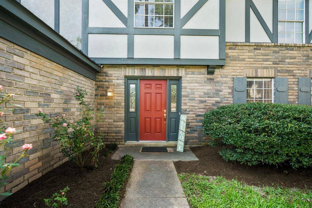 A vibrant red front door stands as a bold and welcoming entrance