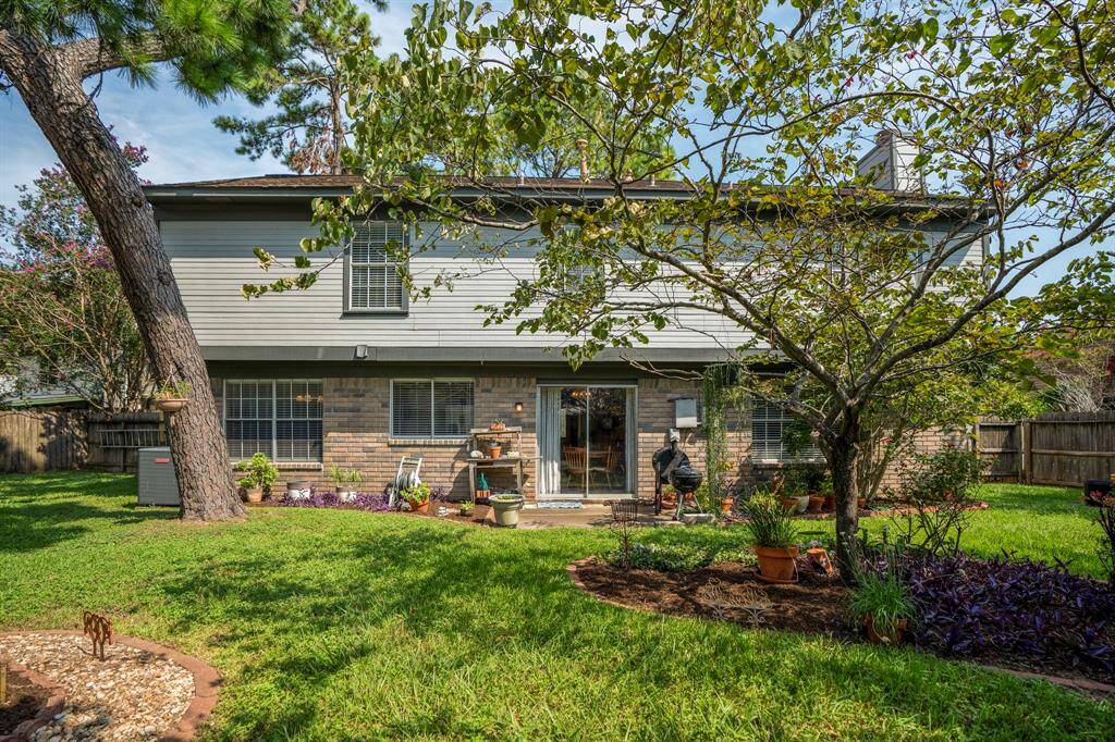 This is a two-story home with a mix of brick and siding, featuring a spacious backyard with mature trees and a privacy fence.