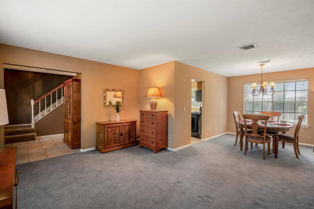 This is a spacious, well-lit formal living room and dining room featuring neutral-toned walls and carpet flooring.