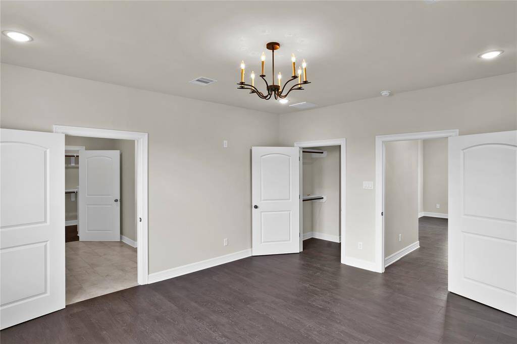 Elegant primary suite featuring an ensuite bath, two spacious walk-in closets with built-in cabinetry.