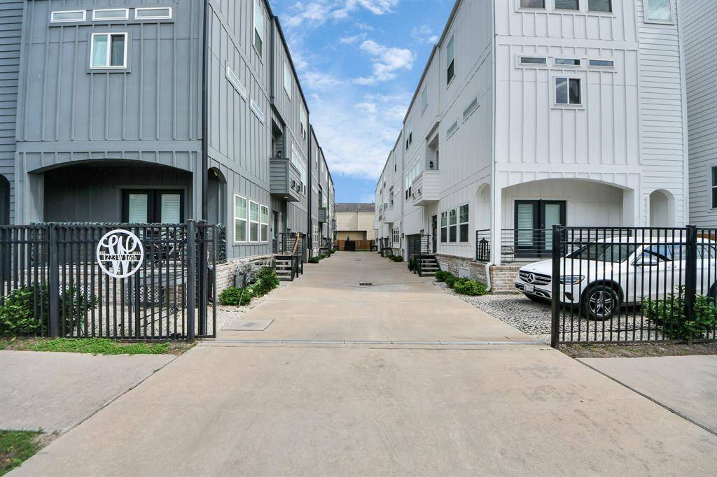 Modern townhouses with a sleek design, featuring a gated entry and private drive. The units are painted in contrasting gray and white, and there's a small landscaped area. Ideal for buyers seeking a contemporary living space.