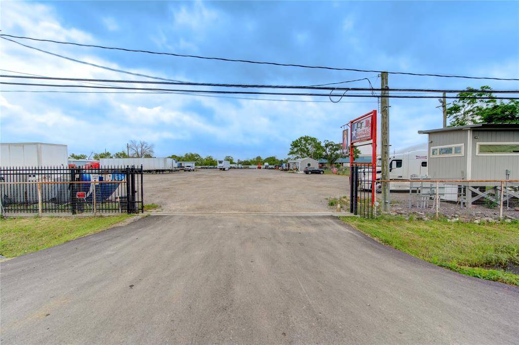 The photo shows a large, gated gravel lot suitable for parking or storage, with trailers and a small building on site. It's ideal for commercial use or investment purposes.