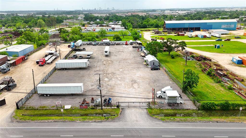 This property features a spacious, fenced lot with ample parking and storage, ideal for commercial use. The surrounding area includes industrial buildings and greenery, offering easy access to major roads.