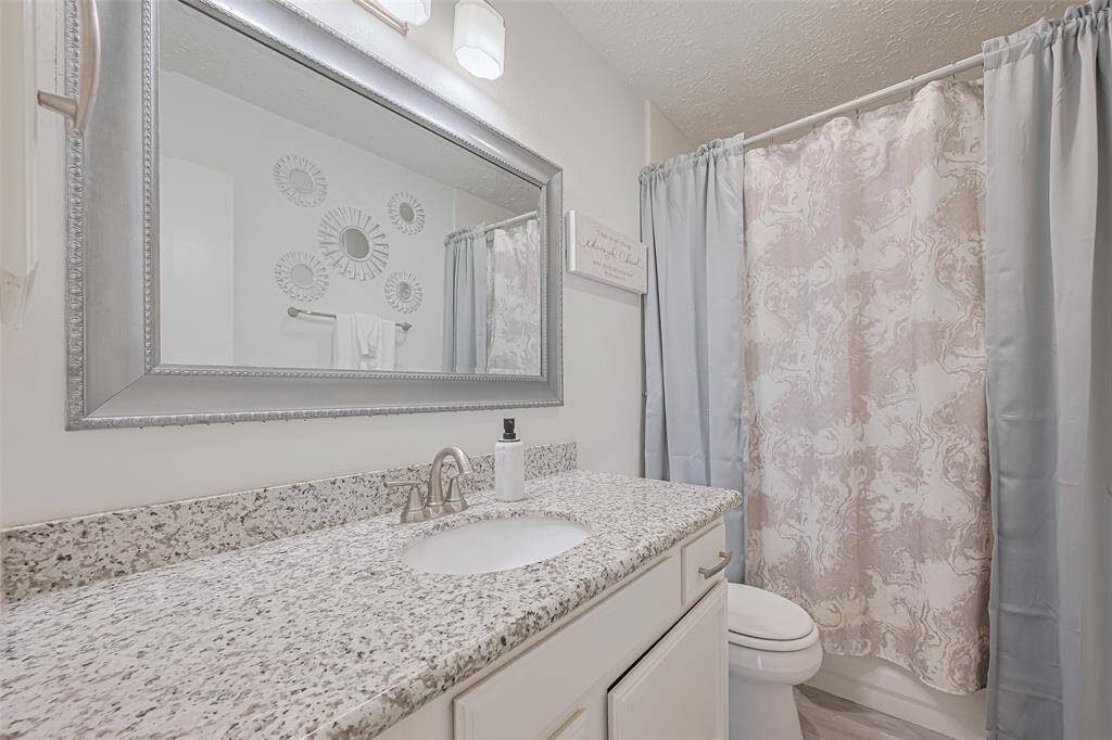 Guest bath. Granite covered vanity with undermount sink and expansive mirror.  All updated fixtures and hardware as well. As in primary there is a combination tub/shower.This primary has combination tub/shower.