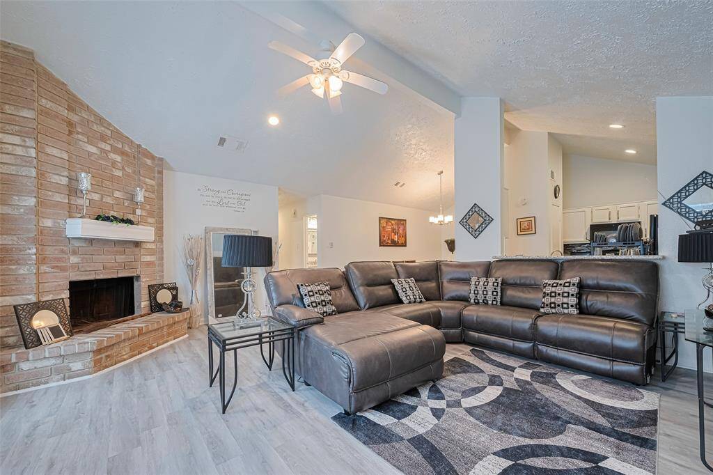 Sun-bathed living area showcasing high beamed ceiling, luxury vinyl plank flooring, ceiling fan and recessed lighting.