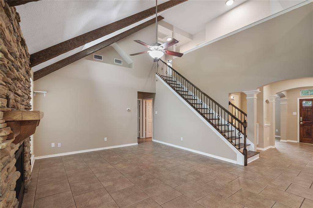 Elegant open-concept layout featuring arched entryways, wrought iron staircase, granite countertops, and a stylish tile-accented kitchen island—blending function with timeless architectural charm.